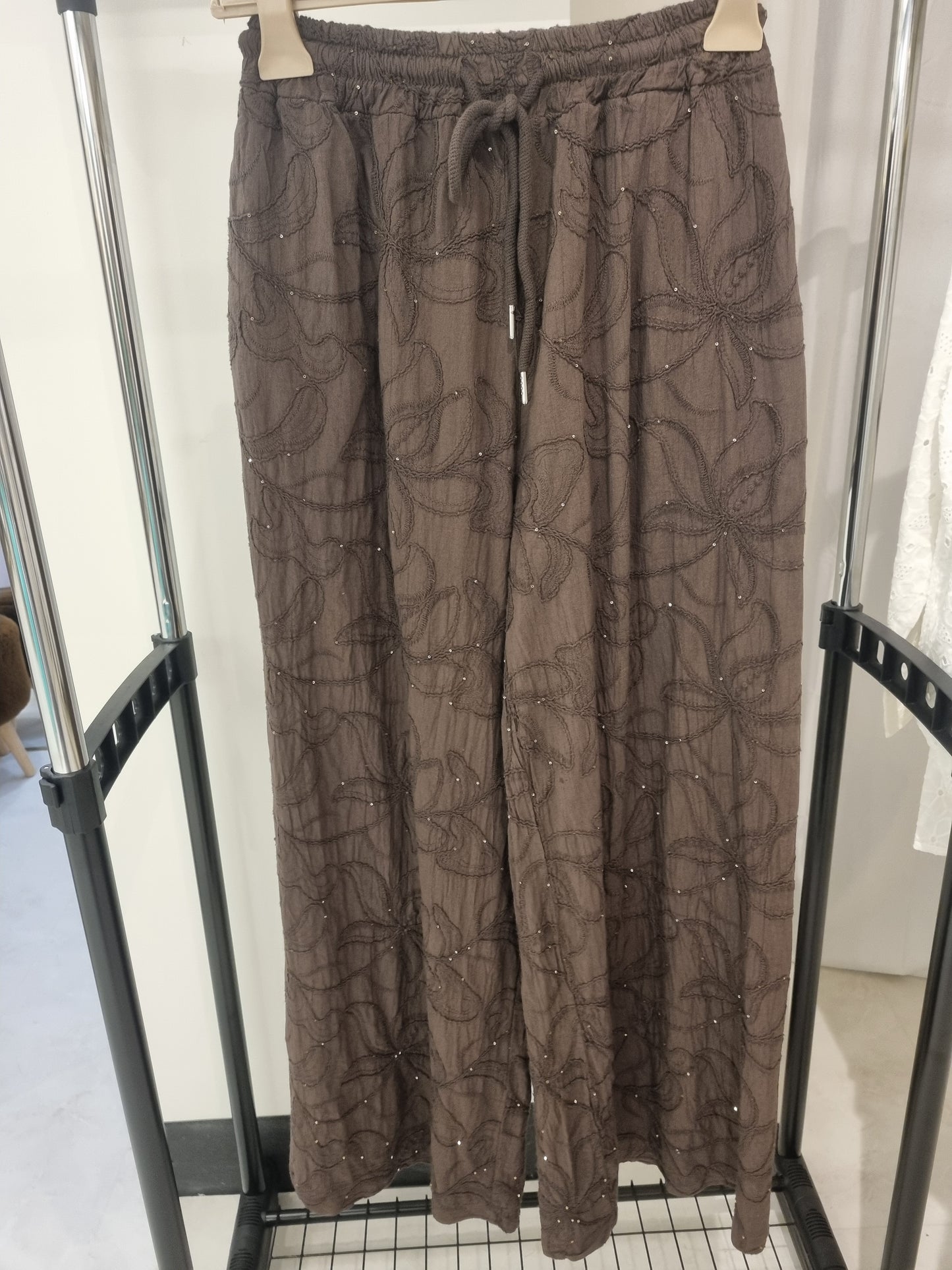 Weit geschnittene braune Hose mit Perlen- und Blumenmuster